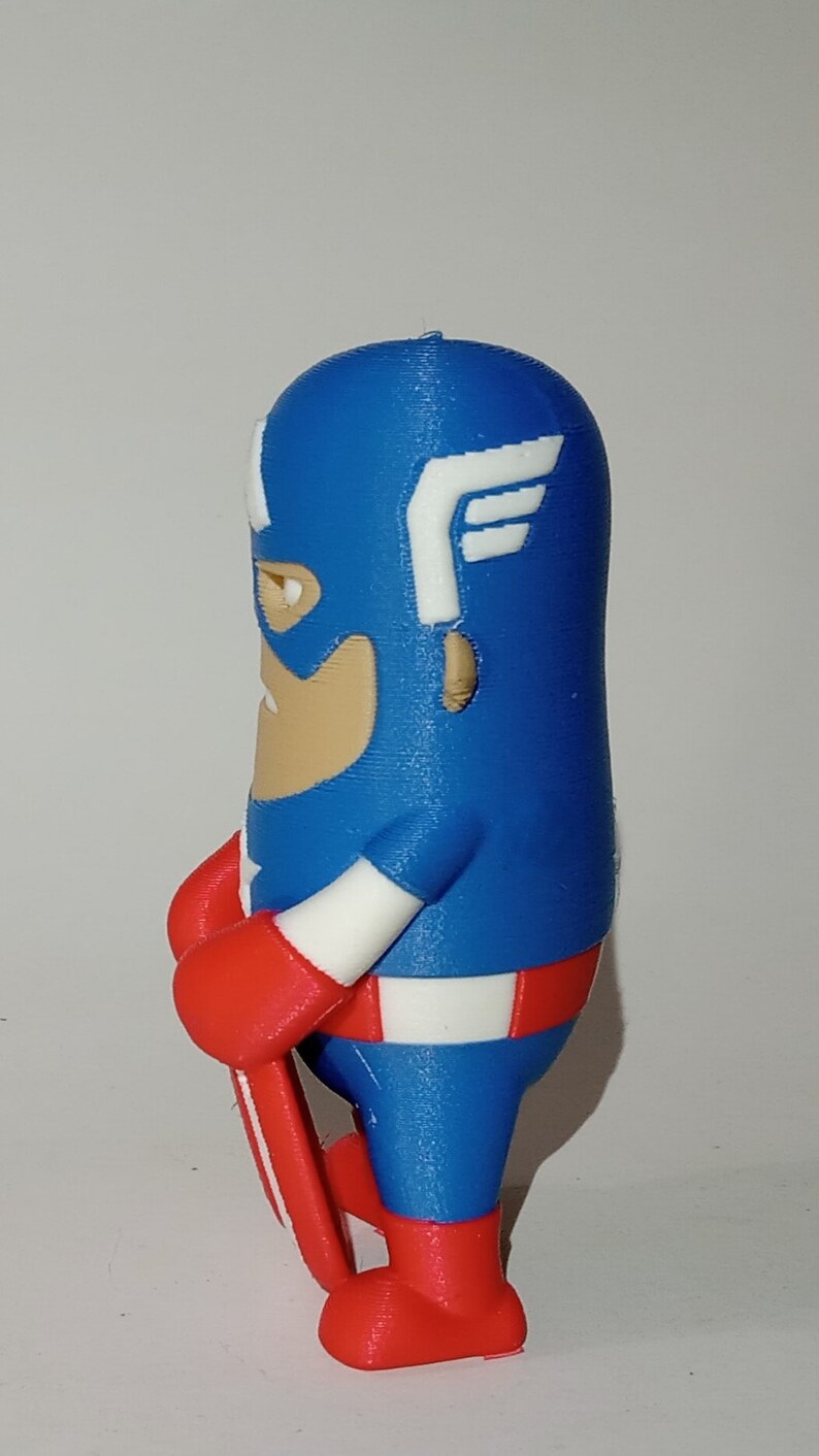 May include: A blue and red 3D printed figurine of Captain America holding a shield. The figurine is in a standing position with its right leg forward. The figurine is wearing a blue and white costume with a red star on the chest. The figurine has a red and white shield in its right hand.