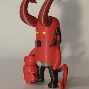 May include: A red and black 3D printed figurine of a demon with horns, a large right arm, and a tail. The demon has yellow eyes and a black belt.