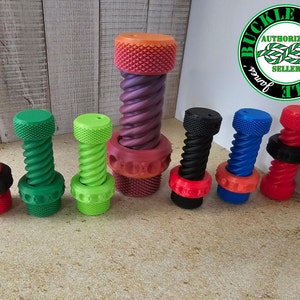 Op de afbeelding: Een set van zeven kleurrijke fidget-speelgoed, elk met een spiraalvormig ontwerp en een getextureerde bovenkant. De speelgoed zijn gemaakt van plastic en zijn verkrijgbaar in rood, groen, oranje, paars, zwart, blauw en rood.