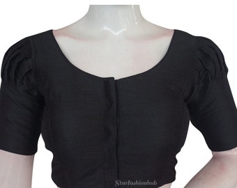 Könnte beinhalten: Eine schwarze Bluse mit rundem Ausschnitt und kurzen Ärmeln. Die Ärmel haben plissierte Details an den Schultern. Die Bluse wird auf einer Schaufensterpuppe präsentiert.