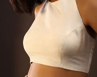 May include: A white halter top with a cropped length. The top is made of a smooth, silky fabric.