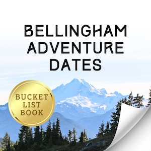 May include: A gold-colored round sticker with the text "Bucket List Book" on a white background with a mountain range in the background. The mountains are covered in snow and the sky is blue.