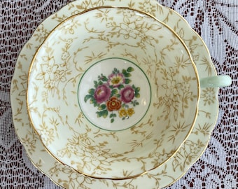 May include: A vintage teacup and saucer set with a delicate floral pattern in shades of pink, yellow, and green. The cup and saucer are both trimmed with a gold band.