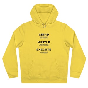 Op de afbeelding: Gele hoodie met een zwarte print die "GRIND HARD FOCUSED WORK, DONE CONSISTENTLY OVER A PERIOD OF TIME. HUSTLE THE DETERMINATION TO WORK HARD WITH PERSISTENCE FOR THE LIFE YOU DESERVE. EXECUTE PUT IN THE WORK AND LET THE RESULTS TALK FOR THEMSELVES." zegt.
