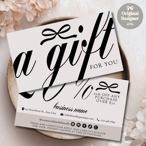 Puede incluir: Dos tarjetas de regalo con diseño de lazo. La tarjeta superior dice "a gift for you" en elegante escritura negra. La tarjeta inferior ofrece un 20% de descuento en compras superiores a 30 €. Incluye información de contacto comercial y redes sociales.