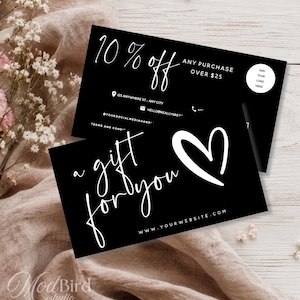 May include: Two rectangular black business cards with white text. The top card displays 10% off any purchase over $25, an address, email, and phone icon. The bottom card features the text a gift for you, a hand-drawn heart, and a website URL.