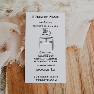 May include: A white label with black text and a line drawing of a candle. The text reads "BUSINESS NAME", "scent name", "CEDARWOOD & AMBER", "SNIFF HERE FOR SCENT", "COCONUT WAX NATURAL FRAGRANCE VEGAN-CRUELTY FREE", "HANDPOURED IN vancouver. b.c.", "BUSINESS NAME WEBSITE.COM".
