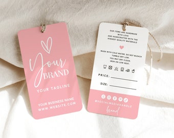 May include: Pink and white hang tag with a heart and the text "Your Brand" and "Your Tagline". The tag also includes the text "Your Business Name" and "www.website.com". The back of the tag has instructions for washing and care, including symbols for machine wash, tumble dry, do not bleach, and iron on low heat. The tag also has space for a price and size.