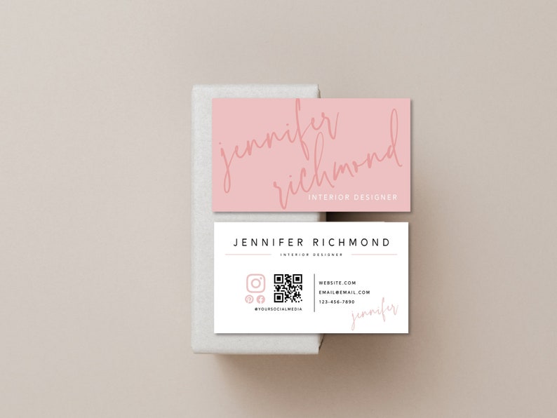 May include: A white business card with a pink border and a QR code. The text on the card reads "Jennifer Richmond, Interior Designer, Website.com, Email@email.com, 123-456-7890".
