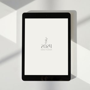 May include: A black tablet computer with a white screen displaying a 2024 weekly planner with a simple design.