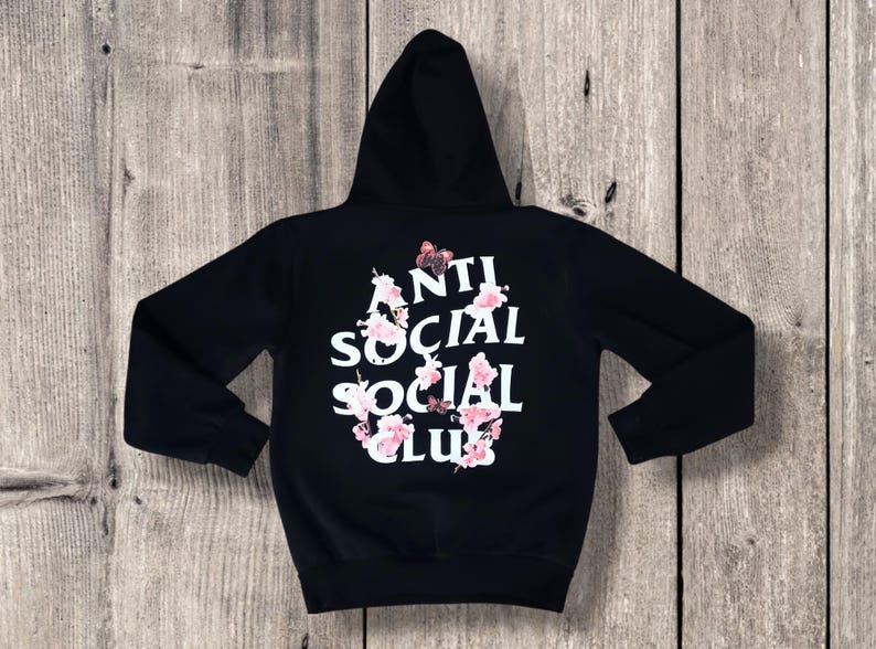 May include: Black hooded sweatshirt with the text "ANTI SOCIAL SOCIAL CLUB" in white, adorned with pink floral and butterfly accents. The hoodie has a drawstring hood and long sleeves.