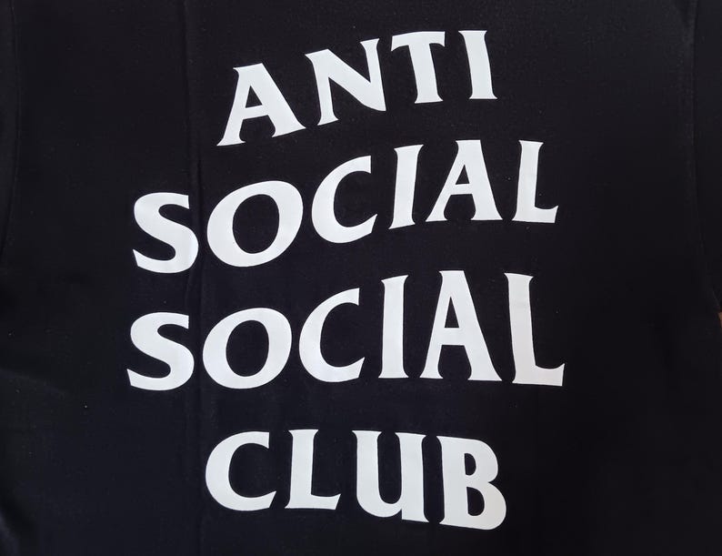 May include: Black t-shirt with the white text "ANTI SOCIAL SOCIAL CLUB" in a stacked arrangement. The text is in a bold, sans-serif font, and the shirt appears to be made of a soft material.