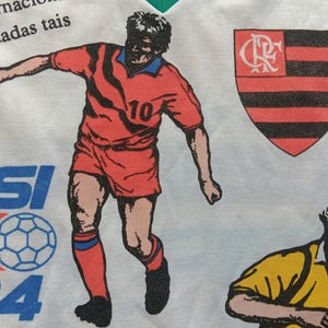 May include: White t-shirt with a red, black, and white soccer player graphic, a black and red crest with the letters "CR", and the text "PEPSI UP'94" in red, blue, and white. The text "ANTI EBS" is visible on the right side of the shirt.