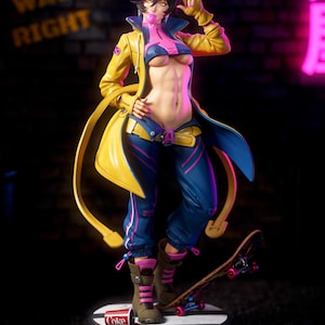 Peut inclure: Une figurine de style anime représentant un personnage aux cheveux courts foncés, portant une veste jaune, un pantalon bleu et des touches roses. Le personnage fait une bulle rose, porte des lunettes et se tient sur un socle avec un skateboard et un gobelet Coke renversé.