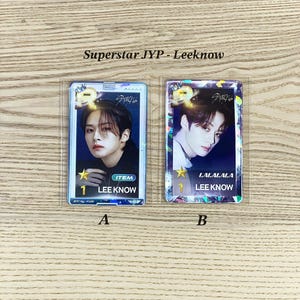 May include: Two holographic photo cards featuring a K-pop idol. The cards are in a clear plastic sleeve. The card on the left has the text "ITEM 1 LEE KNOW" and the card on the right has the text "LALALALA LEE KNOW".