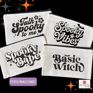 May include: Four white canvas zipper pouches with black text. The pouches have phrases like "Talk Spooky to me", "Spooky Vibes", "Spooky Babe", and "Basic Witch". The word "Personalizable" is in a purple box.