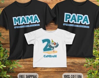 May include: Three black t-shirts with white text. The shirts say "Mama of the Puffin Rock Adventurer", "Papa of the Puffin Rock Adventurer", and a white t-shirt with a cartoon puffin wearing a party hat and the number 2. The text on the white shirt says "Cameron".