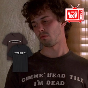 May include: A man wearing a dark brown t-shirt with the text "Gimme' Head Till I'm Dead" printed in white. The shirt is a popular design and is available in multiple colors.