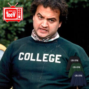 May include: A dark green sweatshirt with the word "COLLEGE" printed in white on the front. The sweatshirt is being worn by a man with a serious expression on his face.