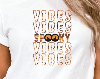 May include: White t-shirt with the text "VIBES" repeated four times, with the word "SPOOKY" in between the second and third "VIBES". The word "SPOOKY" has two orange eyes with black pupils.