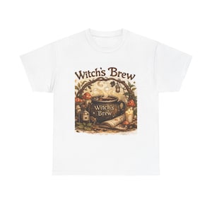 May include: White t-shirt featuring a whimsical illustration with the text "Witch's Brew." The design includes a steaming cauldron, mushrooms, a candle, and a scroll, all in warm, earthy tones. A perfect gift for fans of fantasy and magic.