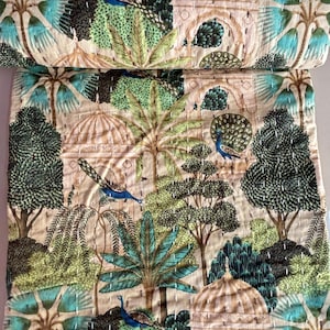 May include: A beige kantha quilt with a repeating pattern of peacocks, trees, and domed structures. The quilt is made of cotton and has a hand-stitched design.