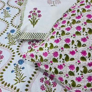 Könnte beinhalten: Weißes Bettwäsche-Set mit floralem Muster mit rosa und grünen Blumen auf weißem Hintergrund. Das Set enthält einen Kissenbezug mit rosa Blumendesign und einem grünen Zickzack-Rand. Die Bettlaken haben ein sich wiederholendes Blumenmuster.