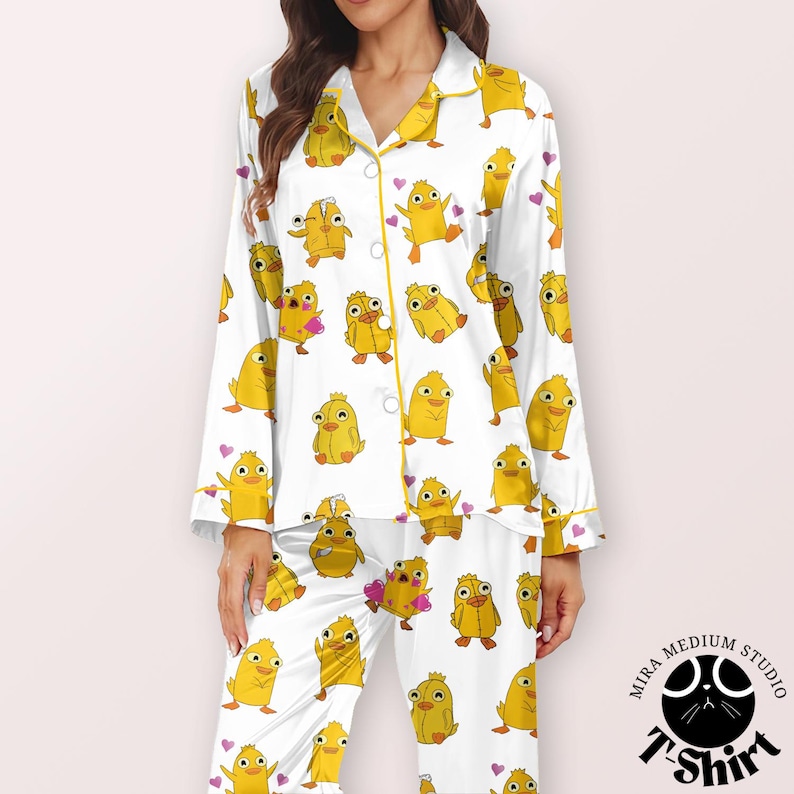 May include: White pajama set with a repeating pattern of yellow cartoon chicks and small pink hearts. The pajamas have yellow trim and buttons. The Mira Medium Studio T-Shirt logo is in the bottom right corner.