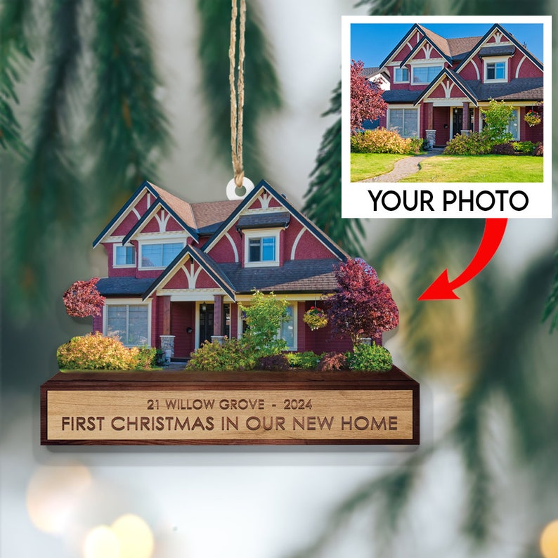 May include: A wooden Christmas ornament shaped like a house with a red roof and white trim. The ornament has a photo of a house with a red roof and white trim. The ornament has the text "21 Willow Grove - 2024 First Christmas in Our New Home".