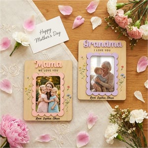 May include: Two wooden photo frames with scalloped pink and lavender borders. One says "Mama, We Love You" and the other says "Grandma, I Love You." Both have photos inside and are decorated with floral accents. A card reads "Happy Mother's Day."