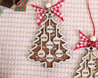 May include: Wooden Christmas tree ornament with a light brown frame and a dark brown interior. The ornament has the year 2025 and names like Landon, Kevin, and Peyton. It is decorated with a red and white bow.