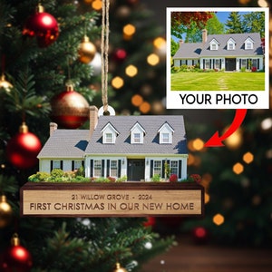 May include: A personalized Christmas ornament featuring a house with a white exterior, black shutters, and a green lawn. The ornament has a wooden plaque with the text "21 Willow Grove - 2024 First Christmas in Our New Home".