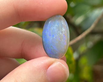 May include: A light blue oval opal gemstone with iridescent blue and green flashes.