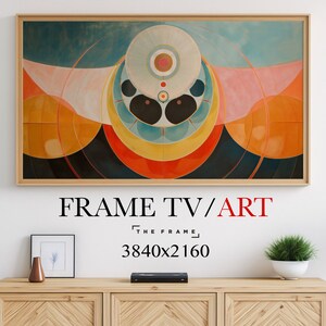 Op de afbeelding: Een ingelijst abstract kunstwerk met een geometrisch ontwerp in tinten rood, oranje, geel, blauw en wit. De print wordt weergegeven op een muur boven een houten kast met een kleine vaas en een fotolijst.