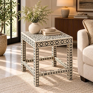 May include: A square side table featuring a dark gray surface with intricate white floral and geometric inlay patterns. The table has four straight legs connected by lower support bars, all decorated with a repeating white cross-shaped motif.
