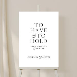 May include: A white wedding sign with black text that reads "To Have & To Hold From This Day Forward Camellia & Austin".