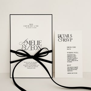 Könnte beinhalten: Schwarze und weiße Hochzeitseinladung mit einer schwarzen Schleife. Die Einladung lautet "Mon Coeur Est A Toi" und "Amelie & Leon". Die Detailkarte lautet "Details & RSVP" und enthält die Kleiderordnung, die Glückwünsche und die RSVP-Informationen.