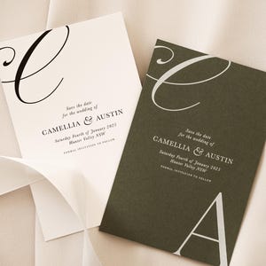 May include: Save the date cards for a wedding. The cards are white and green with black and white calligraphy. The text on the cards reads "Save the date for the wedding of Camelia & Austin. Saturday Fourth of January 2023. Hunter Valley NSW. Formal invitation to follow."