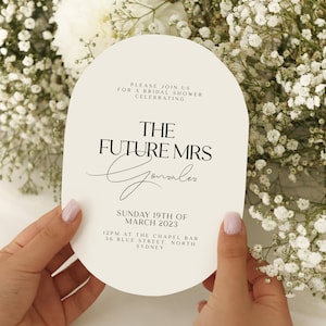 Peut inclure: Invitation de couleur blanche en forme d'ovale pour une fête prénuptiale avec du texte noir. Le texte indique "Veuillez nous rejoindre pour une fête prénuptiale célébrant La Future Mme Gonzalez. Dimanche 19 mars 2023. 12h00 au Chapel Bar, 36 Blue Street, North Sydney."