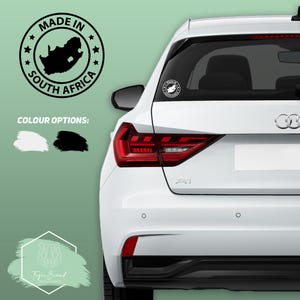 May include: A white car with a black "Made in South Africa" sticker on the back window. The sticker features a map of South Africa and stars around the border. The sticker is available in black or white.