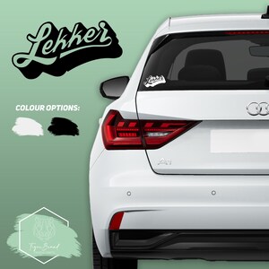 May include: A white car with a black and green "Lekker" sticker on the back window. The sticker is available in white or black.