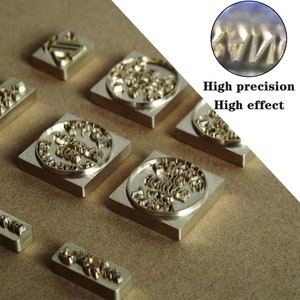 May include: Close-up of several metal stamps with intricate designs. The stamps are square and round, with raised lettering and patterns. The image highlights the high precision and detail of the stamps.
