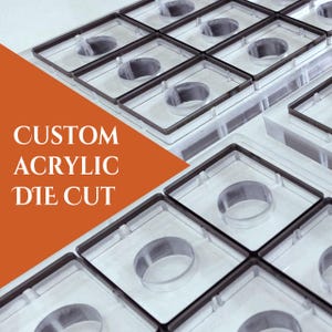 May include: Clear acrylic die-cut pieces arranged in a grid pattern. Each piece has a square frame with a circular cutout in the center. The text "CUSTOM ACRYLIC DIE CUT" is displayed on an orange background.