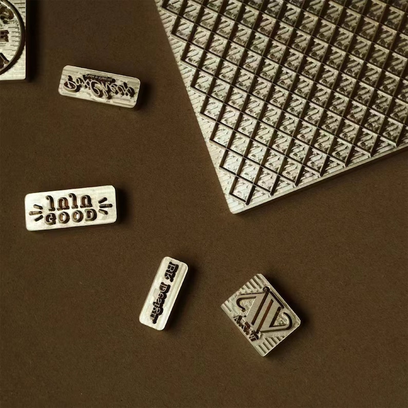 May include: Five wooden stamps with different designs and text. The stamps are on a brown surface. The text on the stamps includes "Good Days", "lala good", "Riz Design", and a design with a trophy.