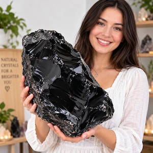 Peut inclure: Un grand morceau brut de cristal d'obsidienne noire avec une surface brillante et réfléchissante et des fractures conchoïdales tranchantes. La pierre présente une couleur noire opaque profonde avec des textures lisses et vitreuses.