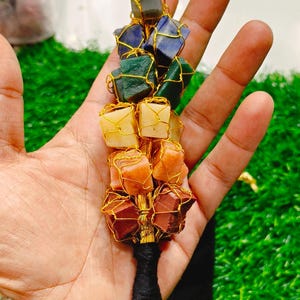 May include: A gold wire wrapped crystal chakra pendulum with seven different colored stones. The stones are amethyst, sodalite, green aventurine, citrine, carnelian, red jasper, and black obsidian.
