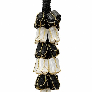 May include: A black and white crystal pendant. Black tourmaline stones are wire-wrapped with gold-colored wire, alternating with selenite crystals. The pendant is suspended from a black cord with a green bead at the top.