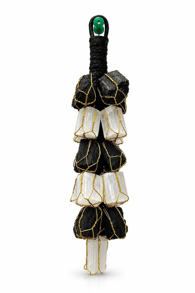 May include: A black and white crystal pendant. Black tourmaline stones are wire-wrapped with gold-colored wire, alternating with selenite crystals. The pendant is suspended from a black cord with a green bead at the top.