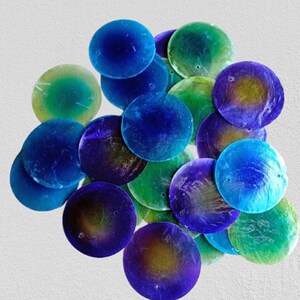 Peut inclure: Un ensemble de sequins ronds et irisés, dans des tons de bleu, vert et violet. Les sequins ont une finition brillante et varient en taille, créant un aspect texturé. Ils sont dispersés sur un fond blanc uni.
