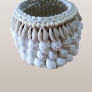 Peut inclure: Un petit panier crocheté blanc avec une bordure décorative de perles blanches et de coquillages blancs.